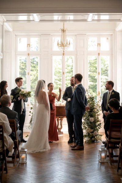 Bride groom and celebrant at alter surrounded by guests